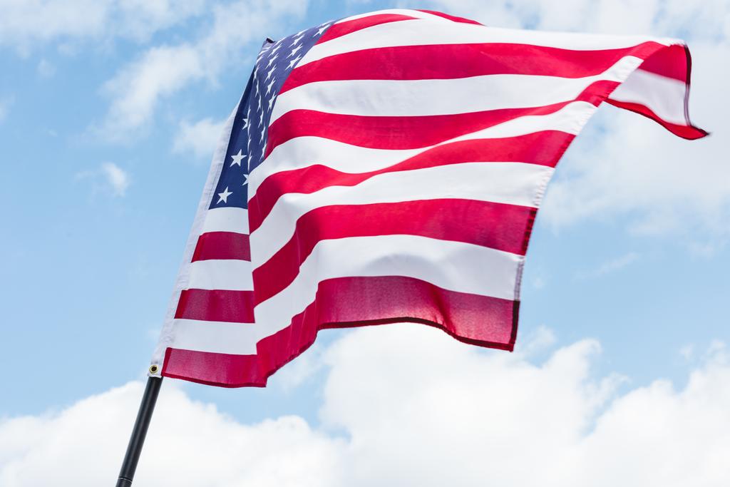 vista ad angolo basso della bandiera degli Stati Uniti con stelle e strisce contro il cielo blu con nuvole
  - Foto, immagini