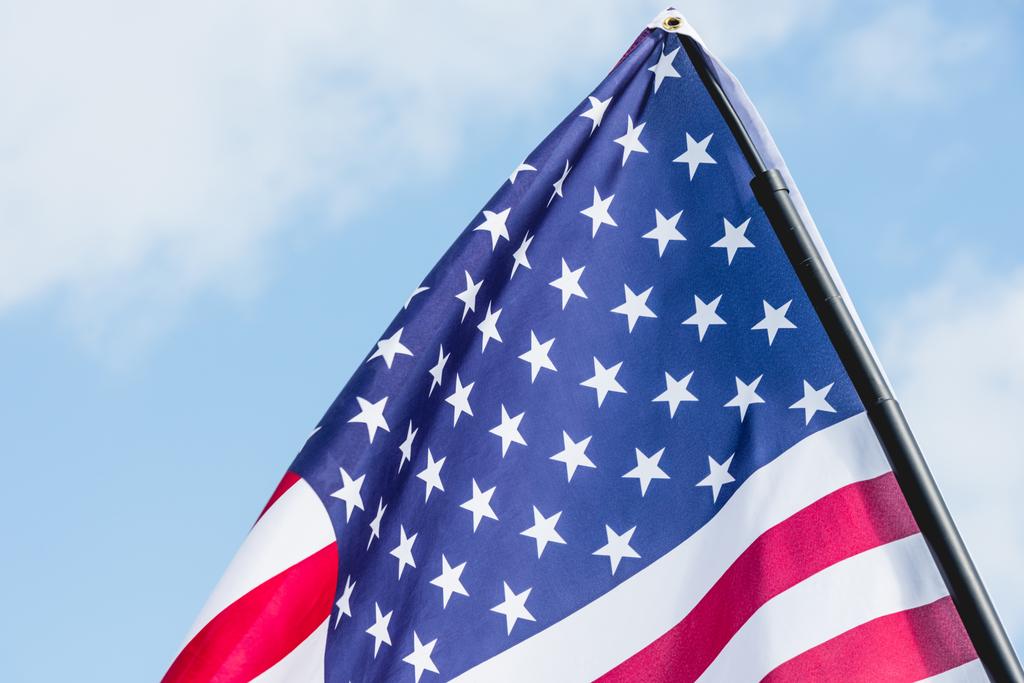 Amerikaanse vlag met sterren en strepen tegen hemel met wolken  - Foto, afbeelding