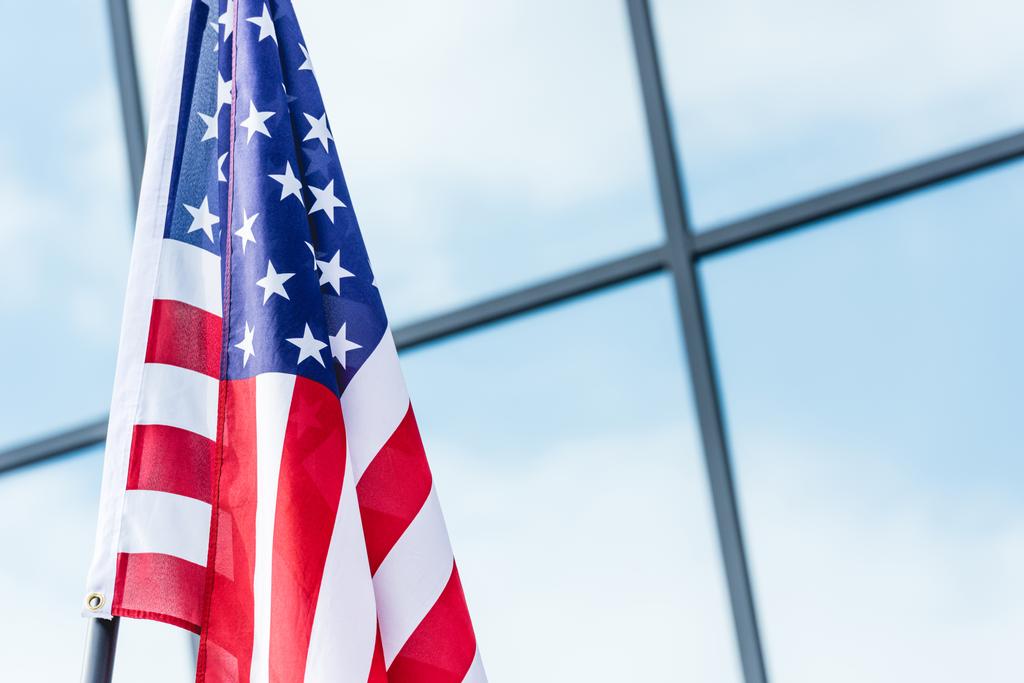 sterren en strepen op de Amerikaanse vlag in de buurt van gebouw met Sky reflectie op Windows - Foto, afbeelding
