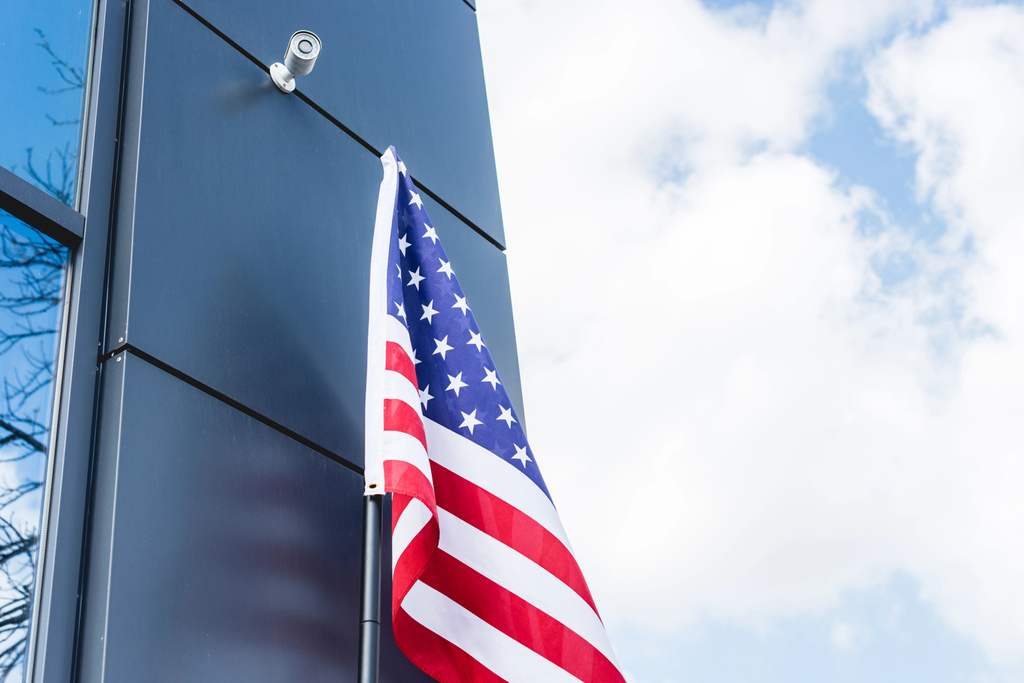 vista de ángulo bajo de la bandera nacional de América con estrellas y rayas cerca de la construcción contra el cielo con nubes
  - Foto, Imagen