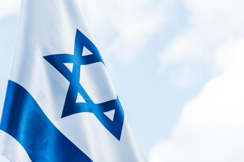 雲と空に対するダビデの青い星とイスラエルの国旗   - 写真・画像