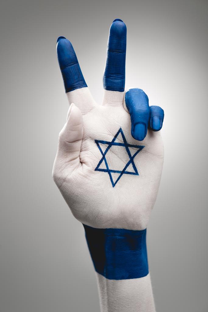 обрезанный вид женской руки с голубой звездой Дэвида, показывающий знак мира на сером
 - Фото, изображение