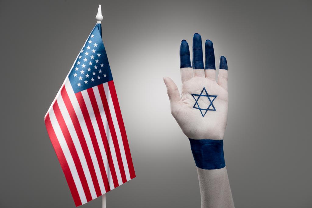 灰色のアメリカ国旗に近いダビデの星を持つ女性の手のクロップドビュー  - 写真・画像
