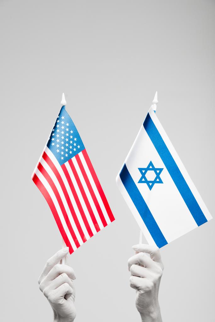 bijgesneden weergave van vrouwelijke handen geschilderd in het wit bedrijf Israël en Amerikaanse vlaggen geïsoleerd op grijs  - Foto, afbeelding