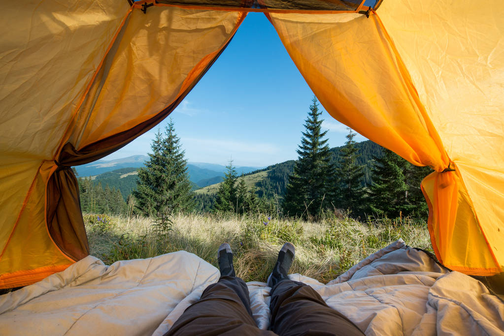 pernas do viajante em uma barraca de acampamento ao ar livre
 - Foto, Imagem
