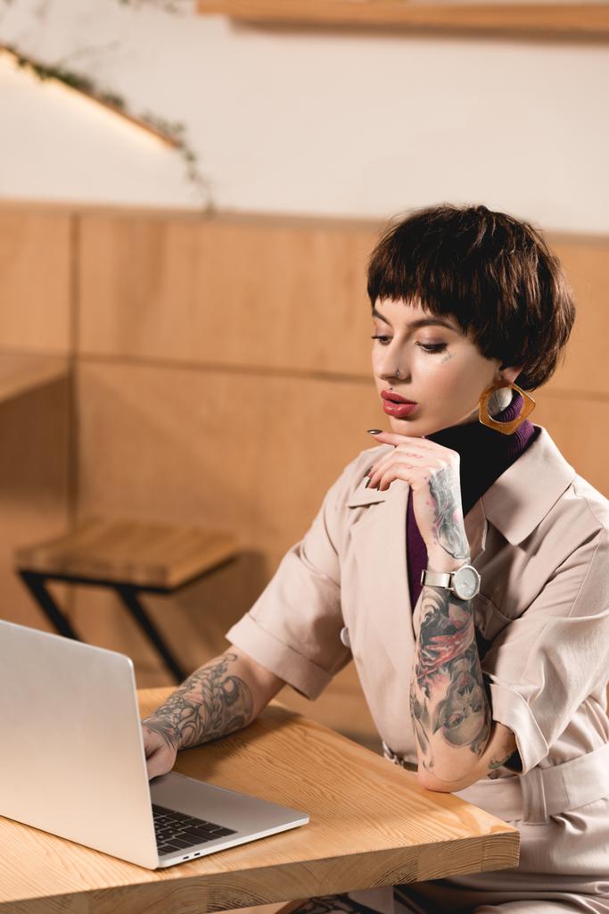 hermosa mujer de negocios usando el ordenador portátil mientras está sentado en la mesa en la cafetería
 - Foto, imagen