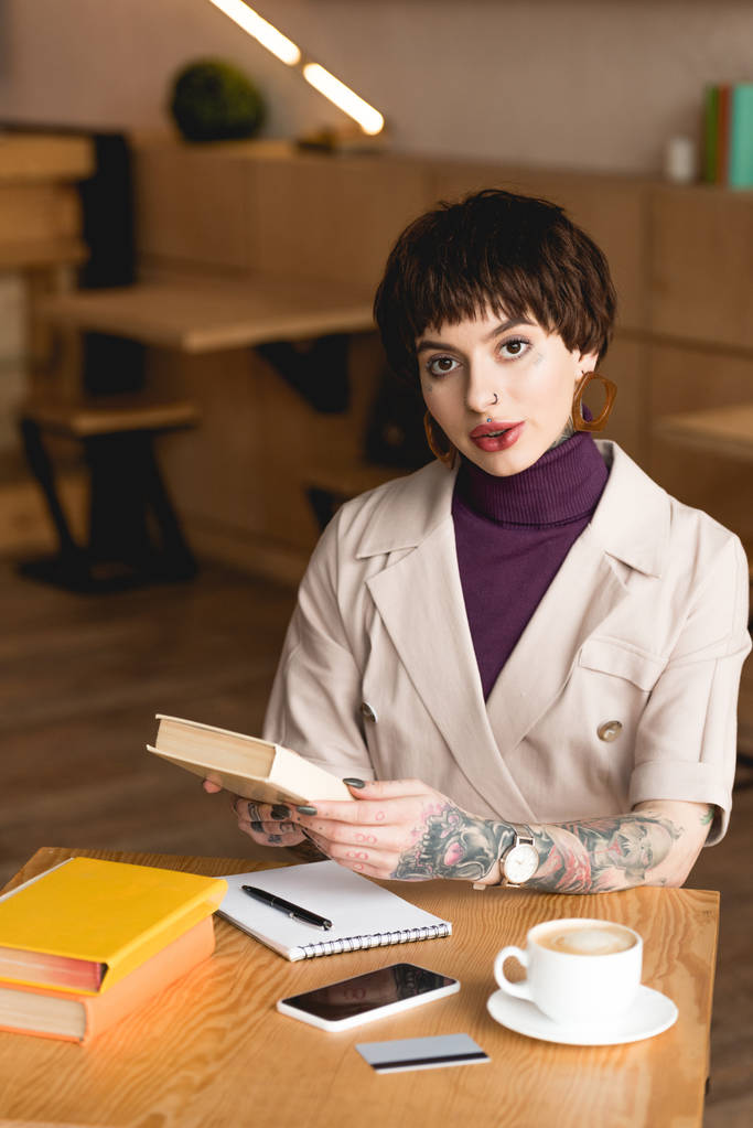 attraktive, selbstbewusste Geschäftsfrau sitzt in der Cafeteria und hält Buch - Foto, Bild