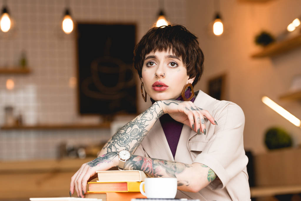 empresária pensativo sentado à mesa com livros e xícara de café na cafetaria
 - Foto, Imagem
