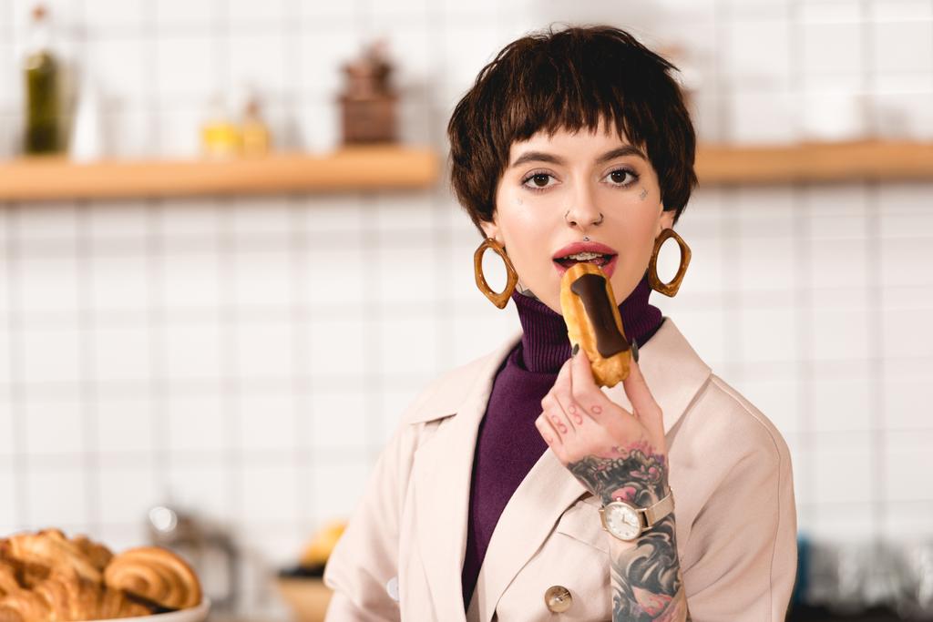 trendige, attraktive Geschäftsfrau probiert köstliche Eclair und blickt in die Kamera - Foto, Bild