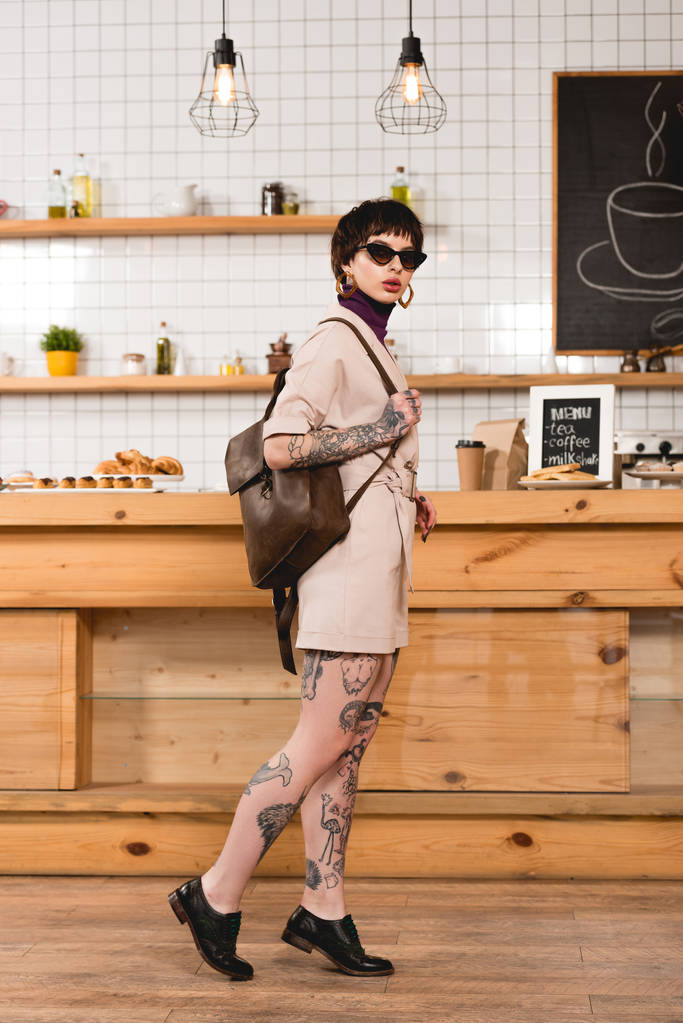 atractiva, mujer de negocios de moda en gafas de sol de pie en el mostrador del bar en la cafetería
 - Foto, imagen