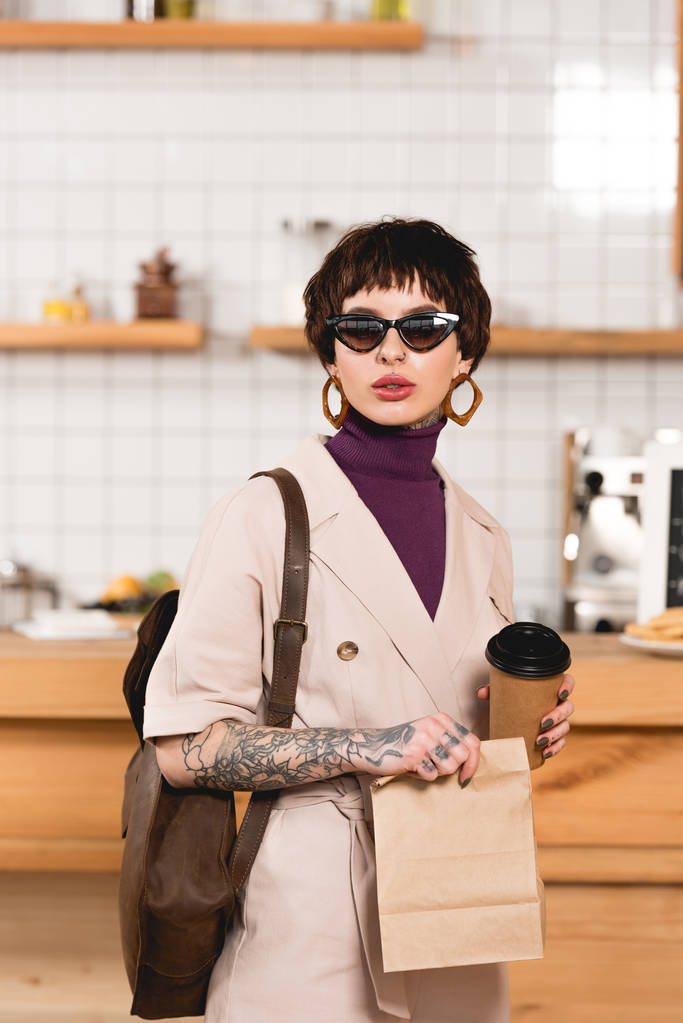 mujer de negocios de moda en gafas de sol con taza desechable y bolsa de papel
 - Foto, imagen