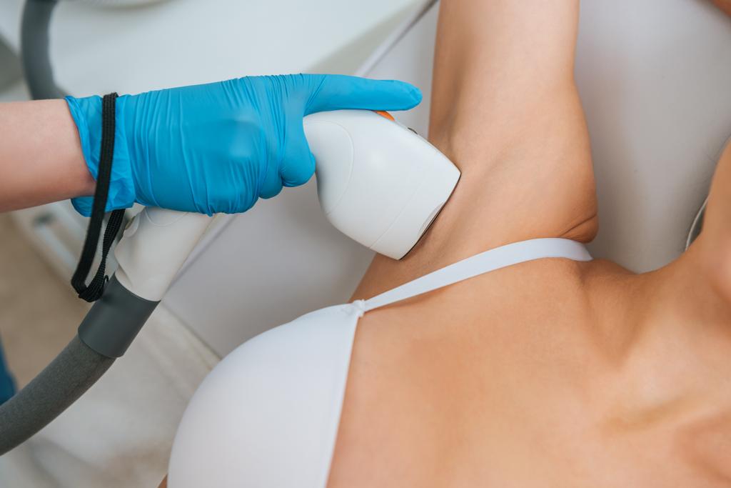 Cropped view of cosmetologist doing laser hair removal procedure on armpit - Photo, Image