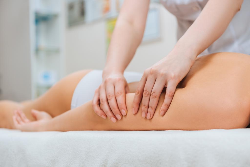 Обрезанный вид массажера, делающего массаж рук девушке на массажном столе
 - Фото, изображение