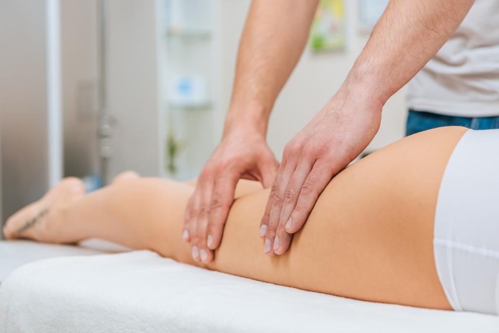 Bijgesneden weergave van masseur doen been massage voor vrouw op massagetafel - Foto, afbeelding