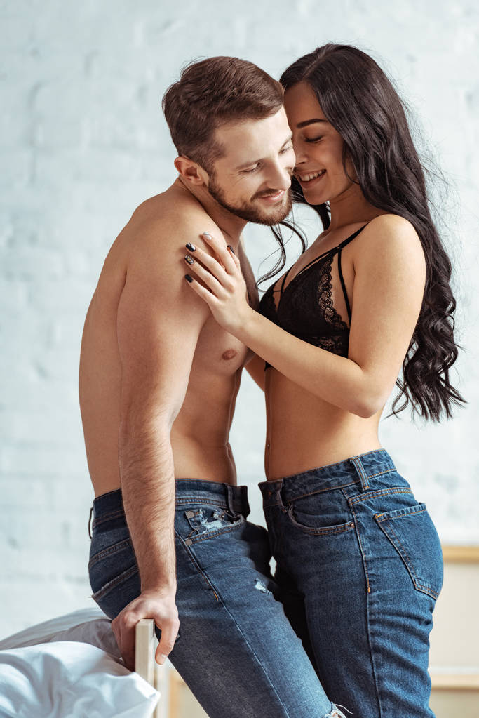 homme beau et musclé étreignant avec belle et souriante femme en soutien-gorge en dentelle dans la chambre
  - Photo, image