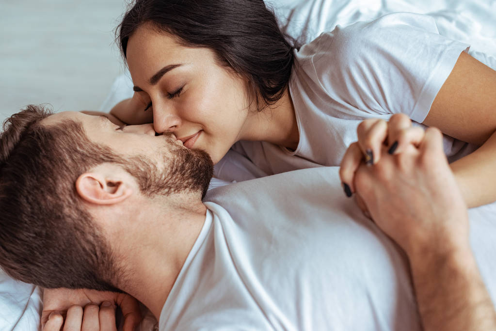 knappe man en mooie vrouw liggend in bed en kussen in slaapkamer  - Foto, afbeelding