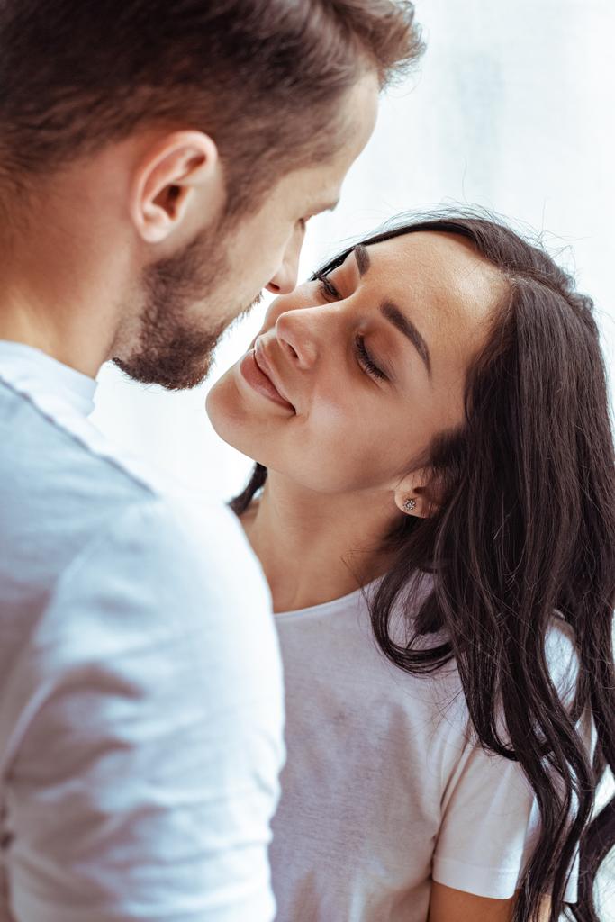 красивий чоловік і красива жінка в футболці дивиться один на одного і цілується
  - Фото, зображення