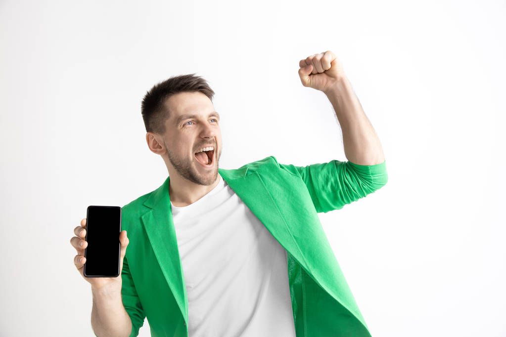 Молодой красивый мужчина показывает экран смартфона и подписания ОК изолированы на сером фоне
 - Фото, изображение