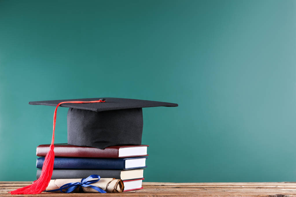 Capa de graduação com diploma e pilha de livros na placa verde ba
 - Foto, Imagem