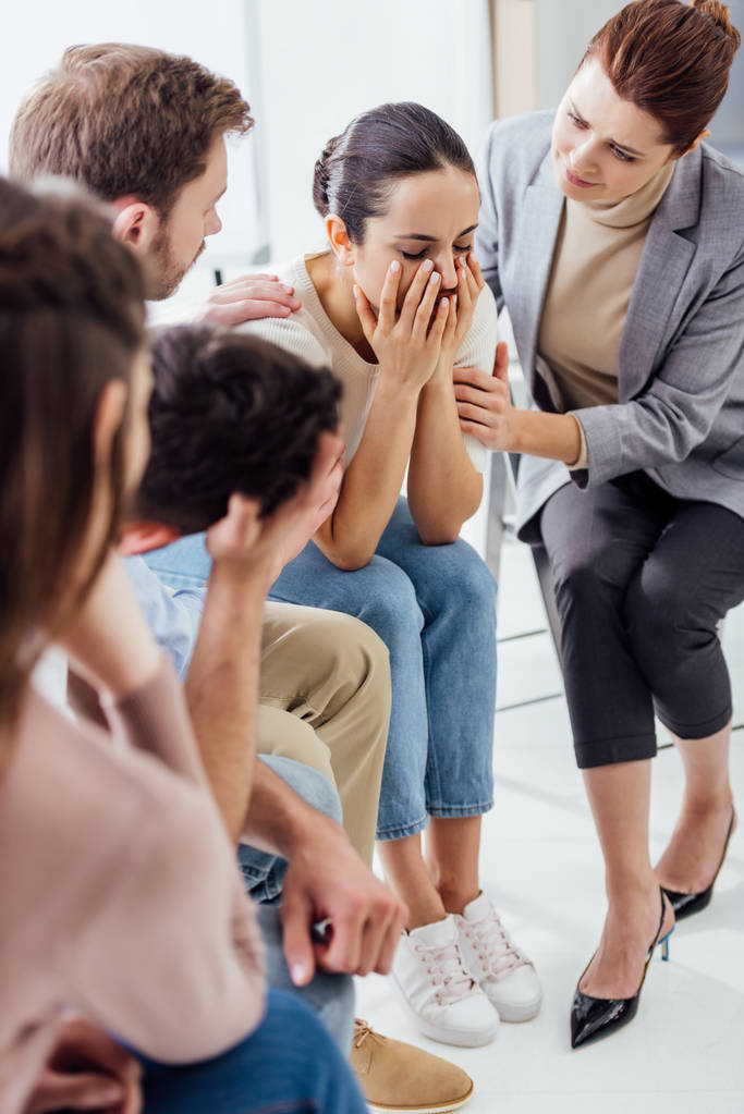 Selektiver Fokus der Frau auf Gesicht und Weinen während Gruppentherapiesitzung - Foto, Bild