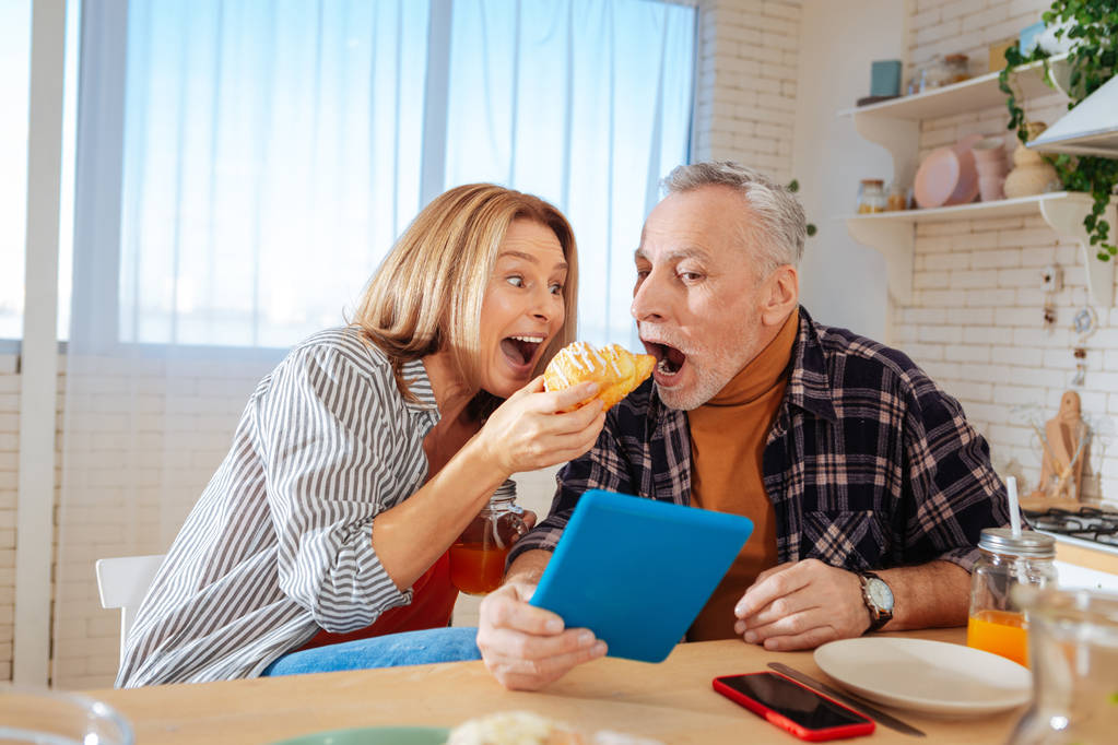 Marido alegre abrindo a boca enquanto tenta croissant
 - Foto, Imagem