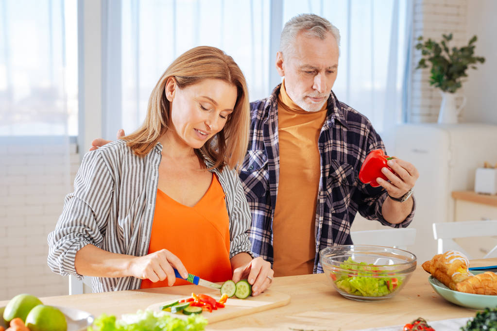 Marido de pie cerca de su esposa cocinar ensalada para la cena
 - Foto, Imagen