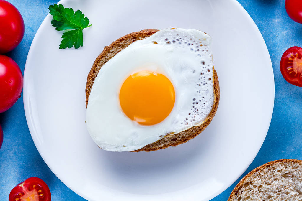 Domowe, smażone jaja kurze na talerzu z pietruszki, pomidory cherry i kok sezam na zdrowe śniadanie. Żywność białkowa. Kanapki z jajkami.  - Zdjęcie, obraz