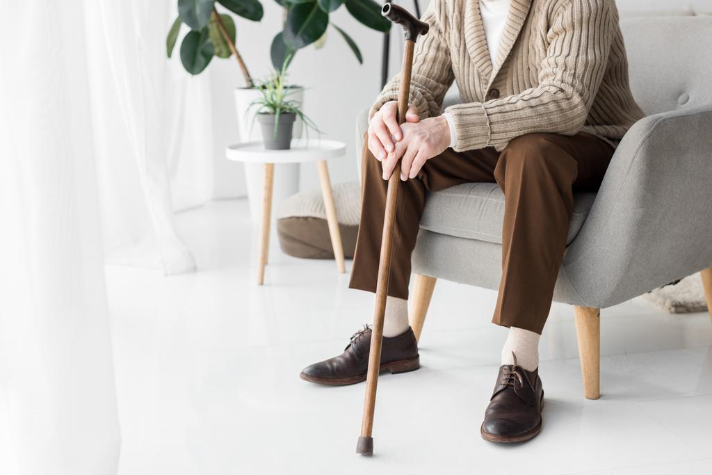 vue recadrée de l'homme âgé assis dans un fauteuil avec canne à pied
  - Photo, image