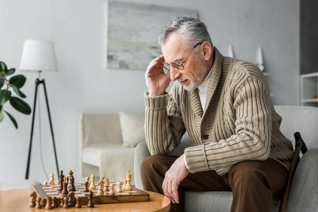 pensivo aposentado homem de óculos pensando ao jogar xadrez em casa
  - Foto, Imagem