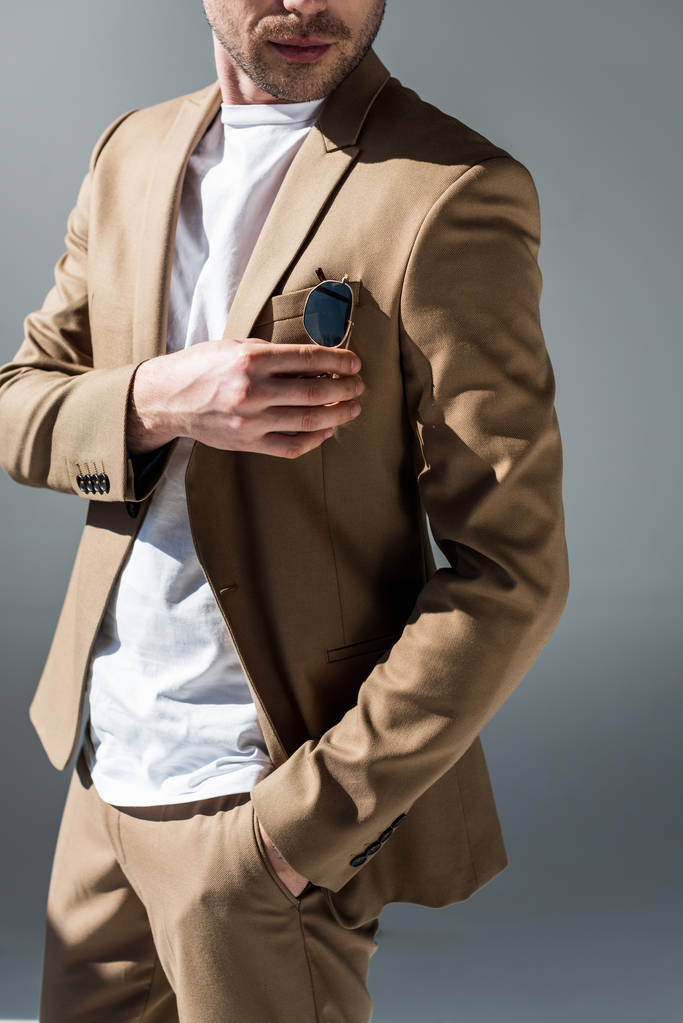 cropped view of man in beige suite with hand in pocket on grey - Photo, Image