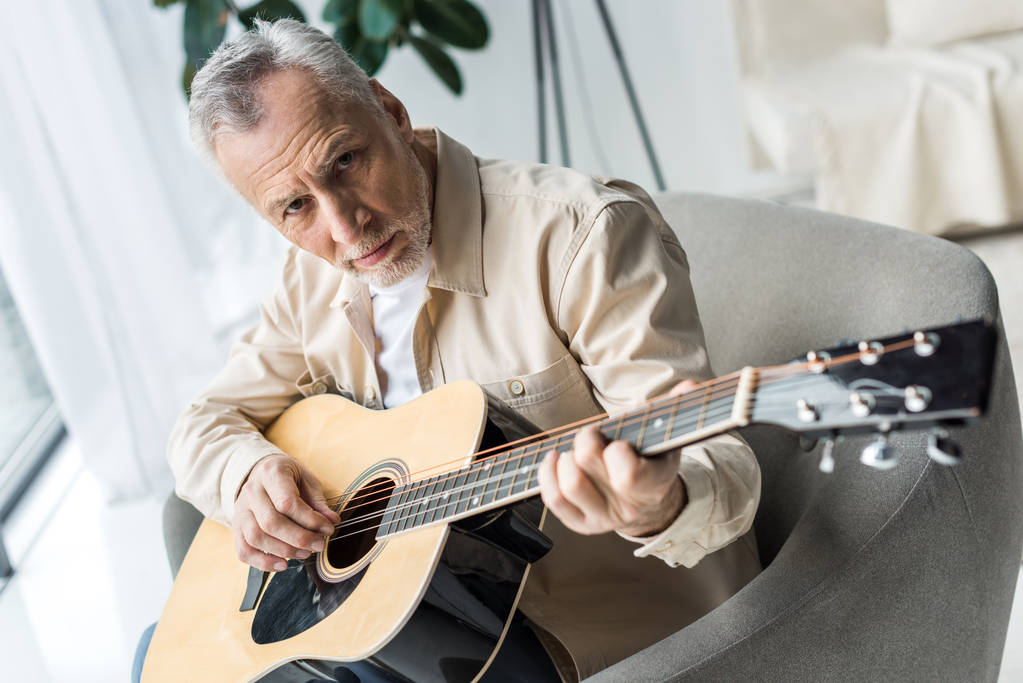 idősebb ember, akusztikus gitáron játszik és látszó-on fényképezőgép  - Fotó, kép