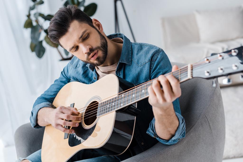 guapo barbudo tocando la guitarra acústica en casa
 - Foto, imagen