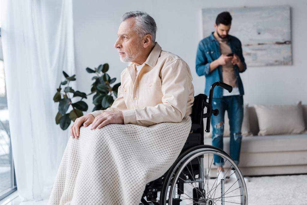 Selektywny fokus niepełnosprawnych starszy człowiek na wózku inwalidzkim w pobliżu syn  - Zdjęcie, obraz