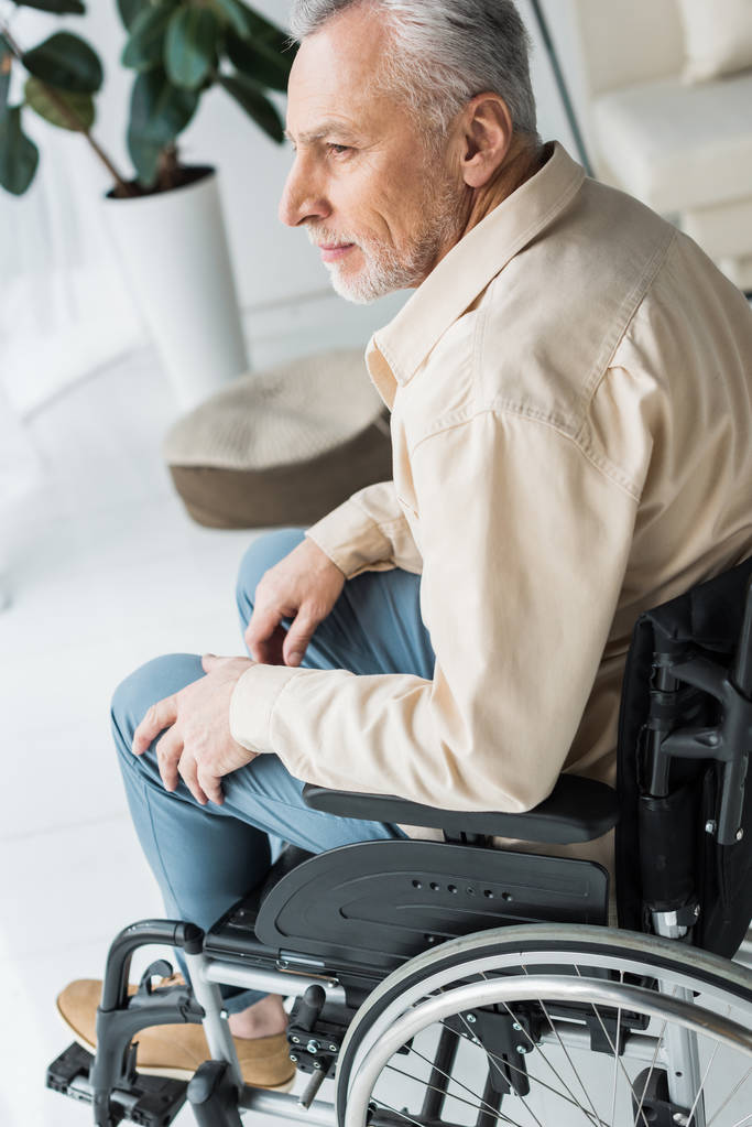 fogyatékkal élő nyugdíjas ember ül tolószékben otthon  - Fotó, kép