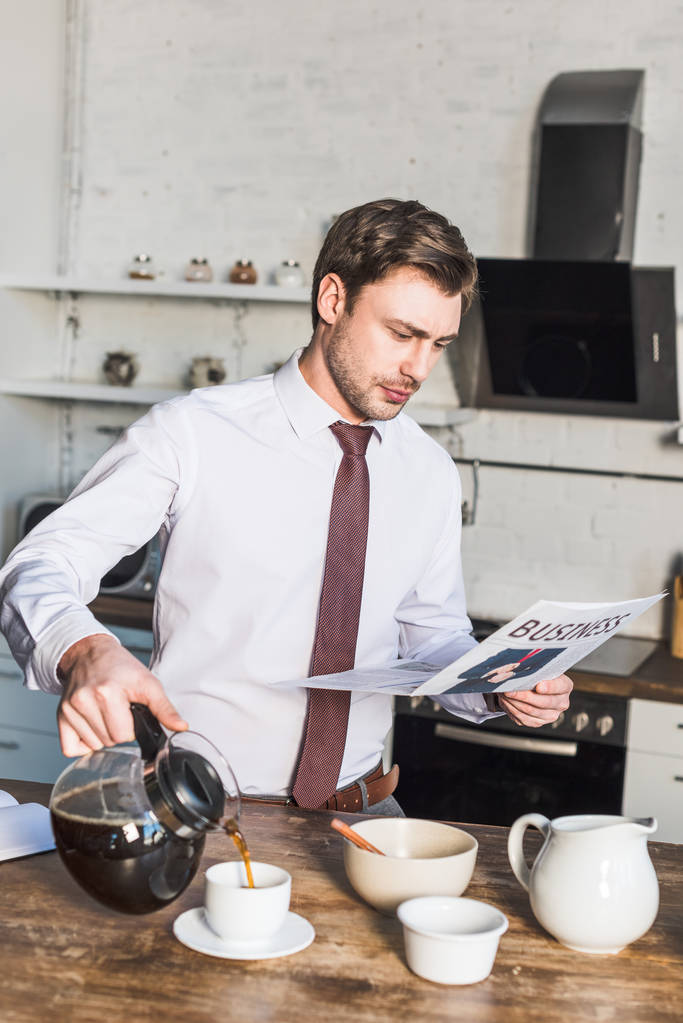 homem bonito derramando café na xícara e lendo jornal de negócios
 - Foto, Imagem