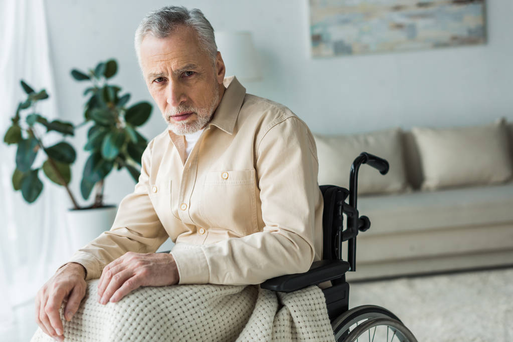 boos gehandicapte gepensioneerde man in de rolstoel zitten en kijken naar camera - Foto, afbeelding