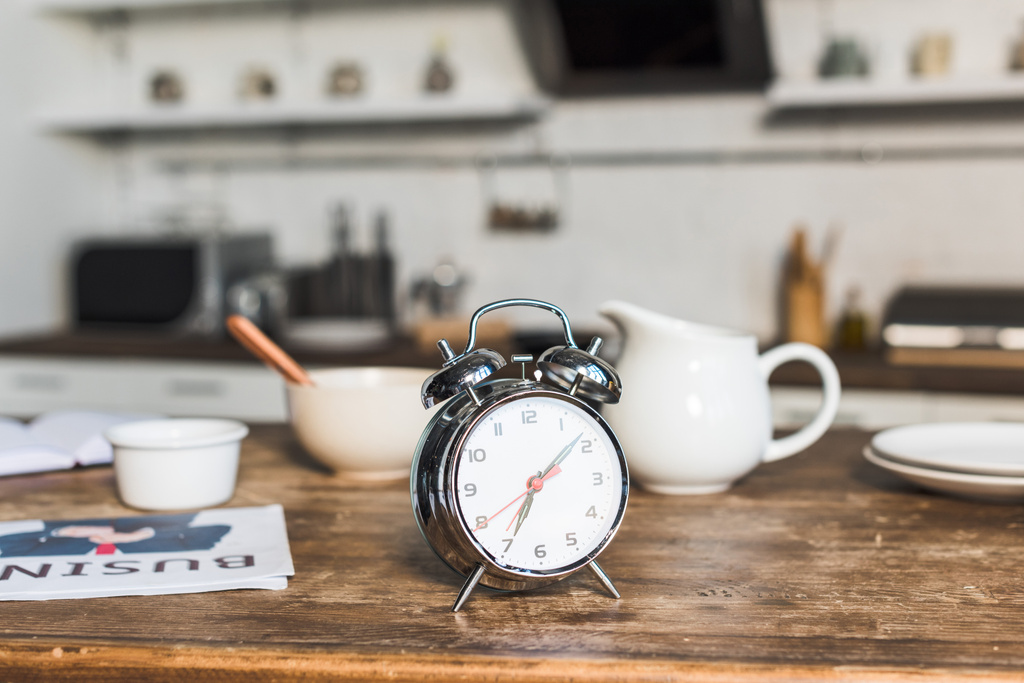 selective focus of vintage alarm clock at wooden table in kitchen - Photo, Image