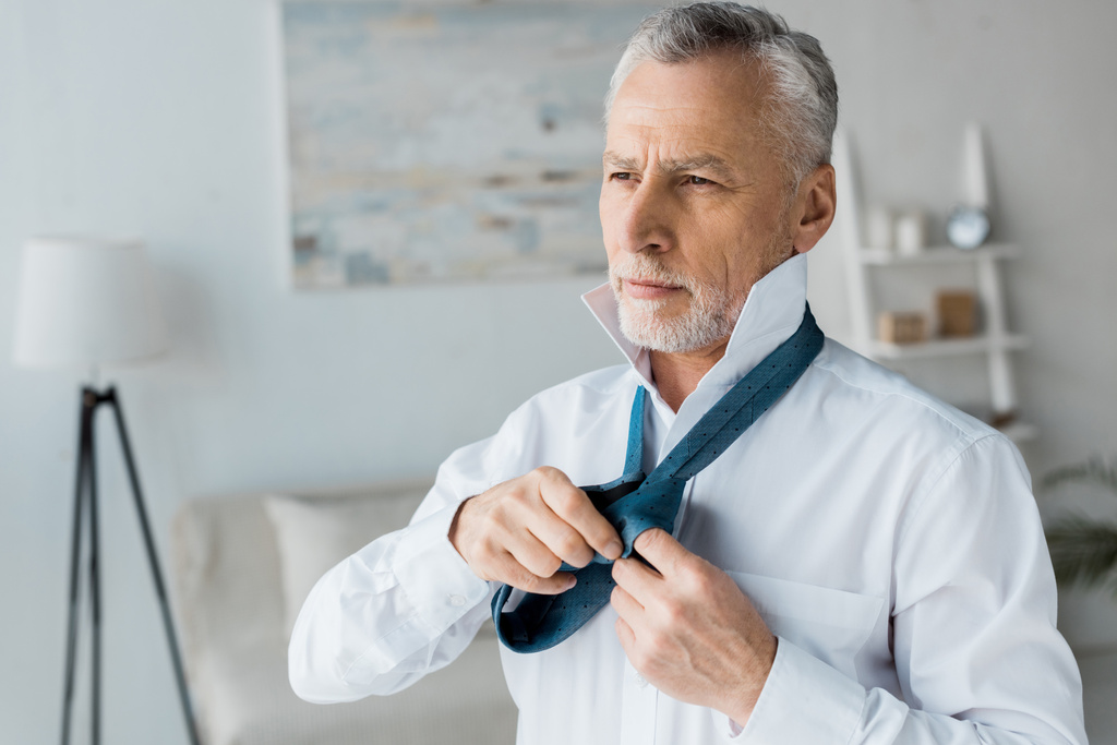 sério e elegante sênior homem amarrando gravata azul em casa
  - Foto, Imagem