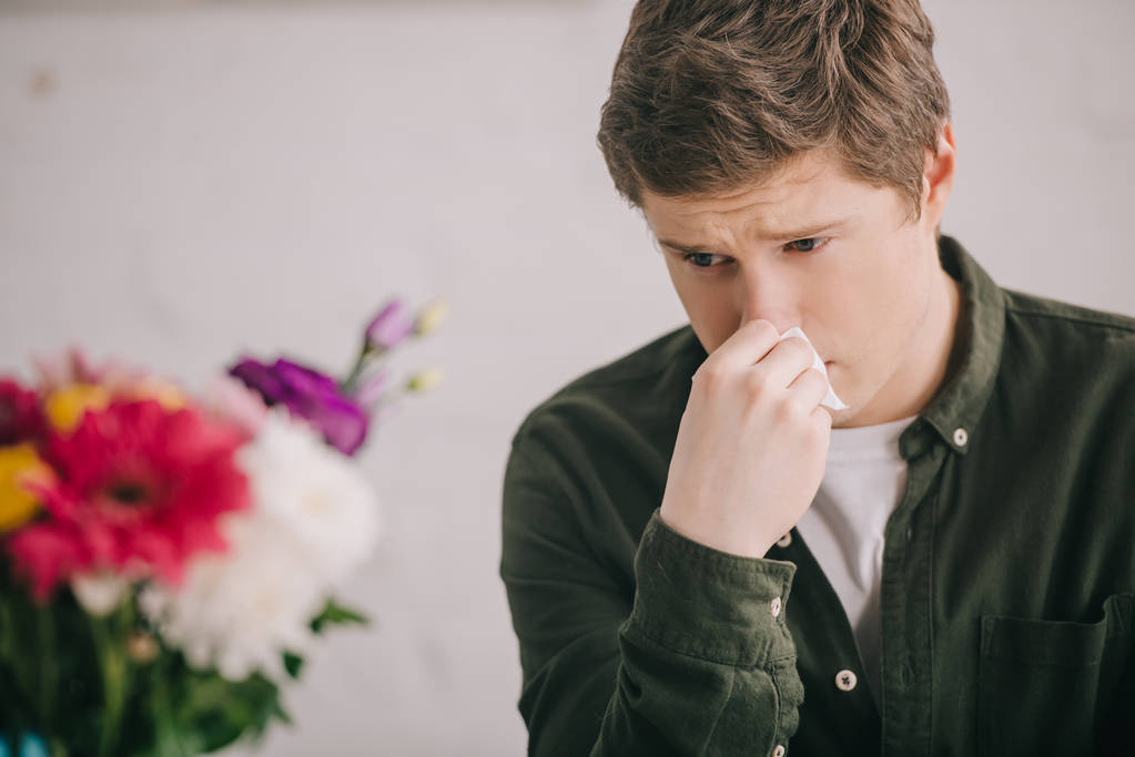 селективное внимание грустного человека с аллергией на пыльцу, смотрящего на цветущие цветы
  - Фото, изображение