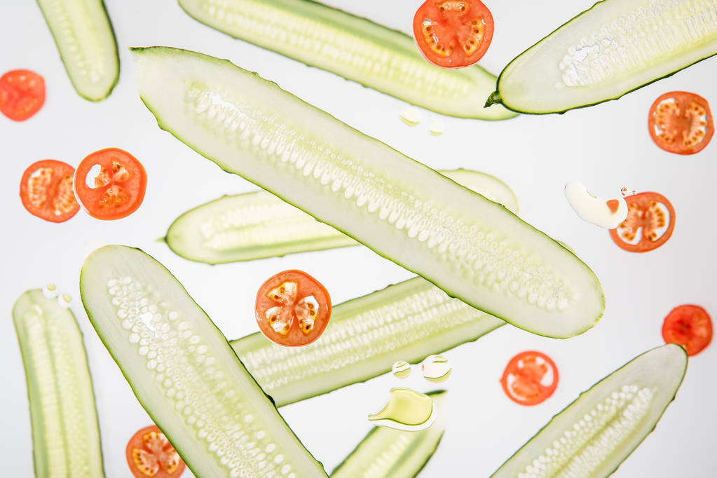achtergrond met gesneden tomaten en komkommers met water bubbels op grijs - Foto, afbeelding