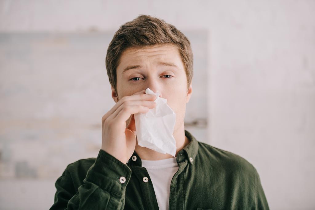 man having allergy and sneezing in tissue and looking at camera - Photo, Image