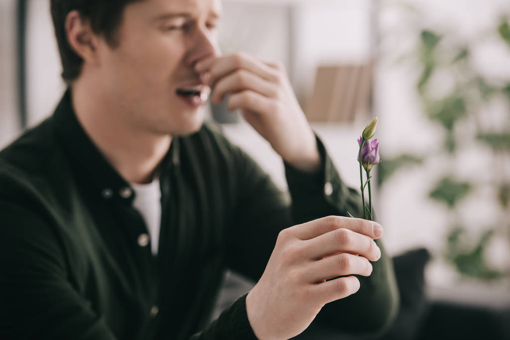selective focus of flower in hand of sneezing man  - Photo, Image