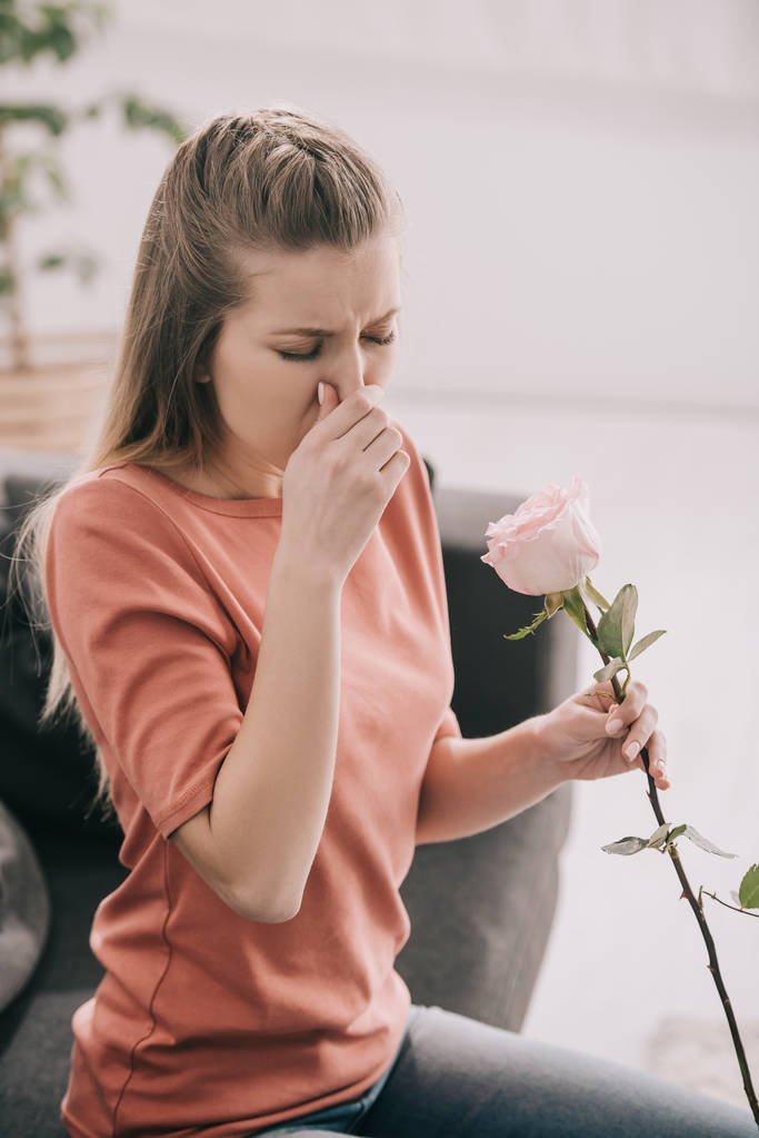 自宅の花を押しながら花粉アレルギーのくしゃみと魅力的なブロンドの女の子  - 写真・画像