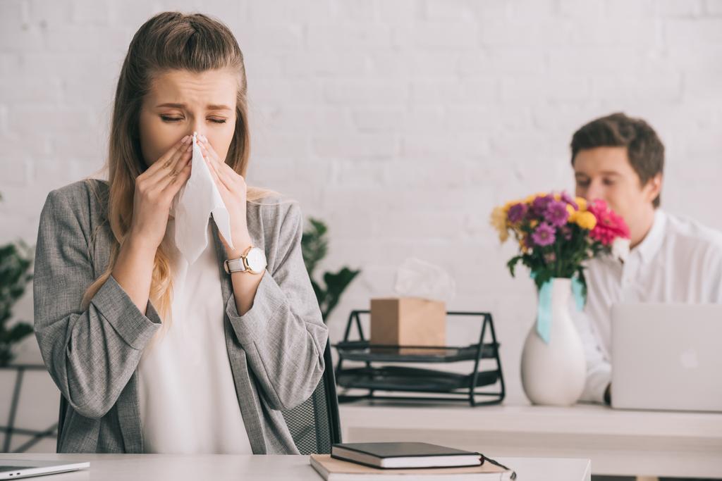 femme d'affaires blonde avec pollen allergie éternuer dans les tissus près de collègue odeur fleurs dans le bureau
  - Photo, image