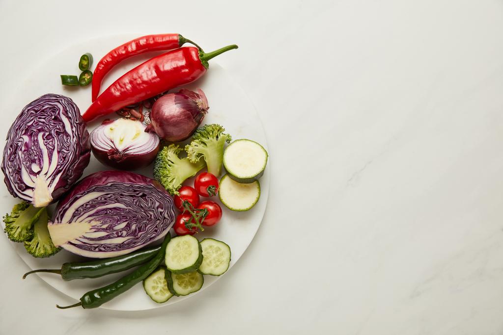Вид сверху на целые и нарезанные овощи на белой поверхности
 - Фото, изображение