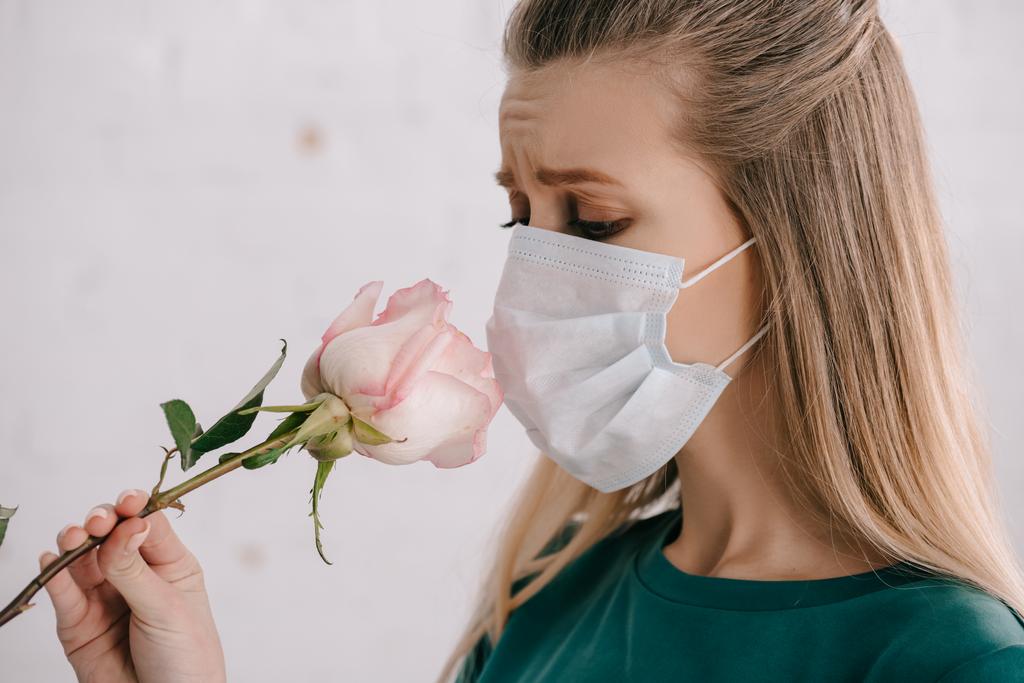 blonde vrouw met pollen allergie dragen van medische masker en ruiken steeg  - Foto, afbeelding