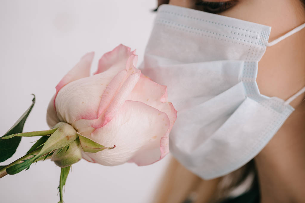 recortado vista de la mujer en médico máscara oliendo rosa
  - Foto, Imagen