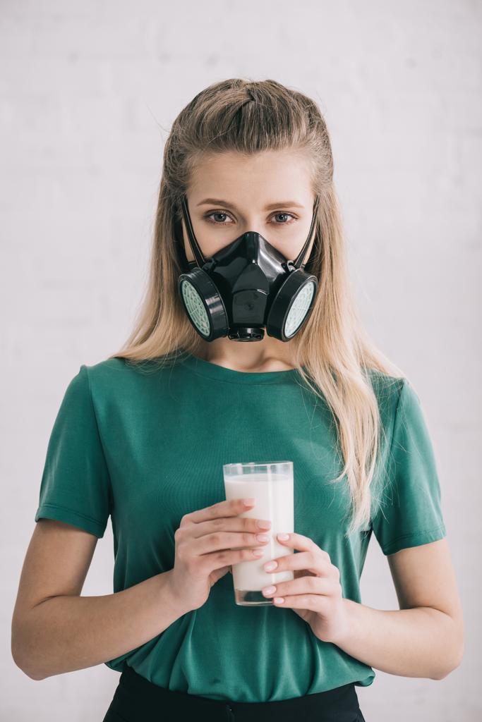 blonde vrouw in respiratoire masker houden glas melk  - Foto, afbeelding