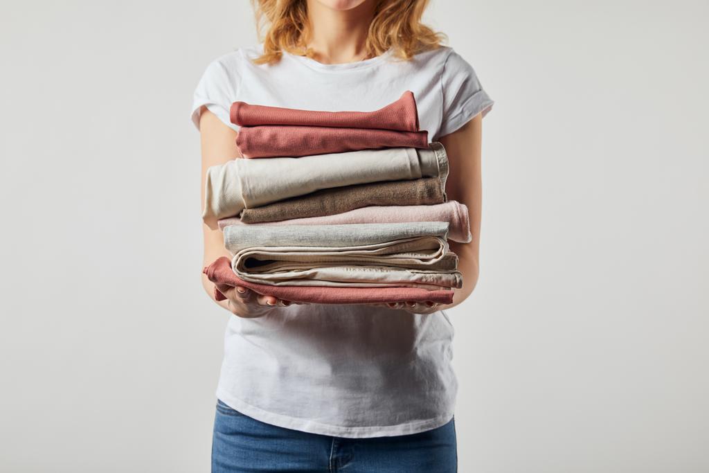 Περικομμένη όψη της γυναίκας που κρατά διπλωμένα σιδερωμένα ρούχα απομονωμένα σε γκρι - Φωτογραφία, εικόνα