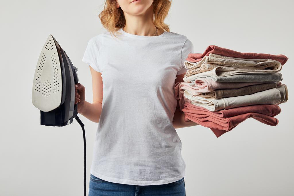 Részleges nő a t-shirt gazdaság vas-és hajtogatott Vasalt ruhát izolált szürke - Fotó, kép